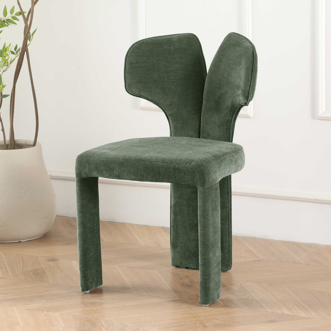 Green sculptural chair in elegant room with herringbone floor and plant