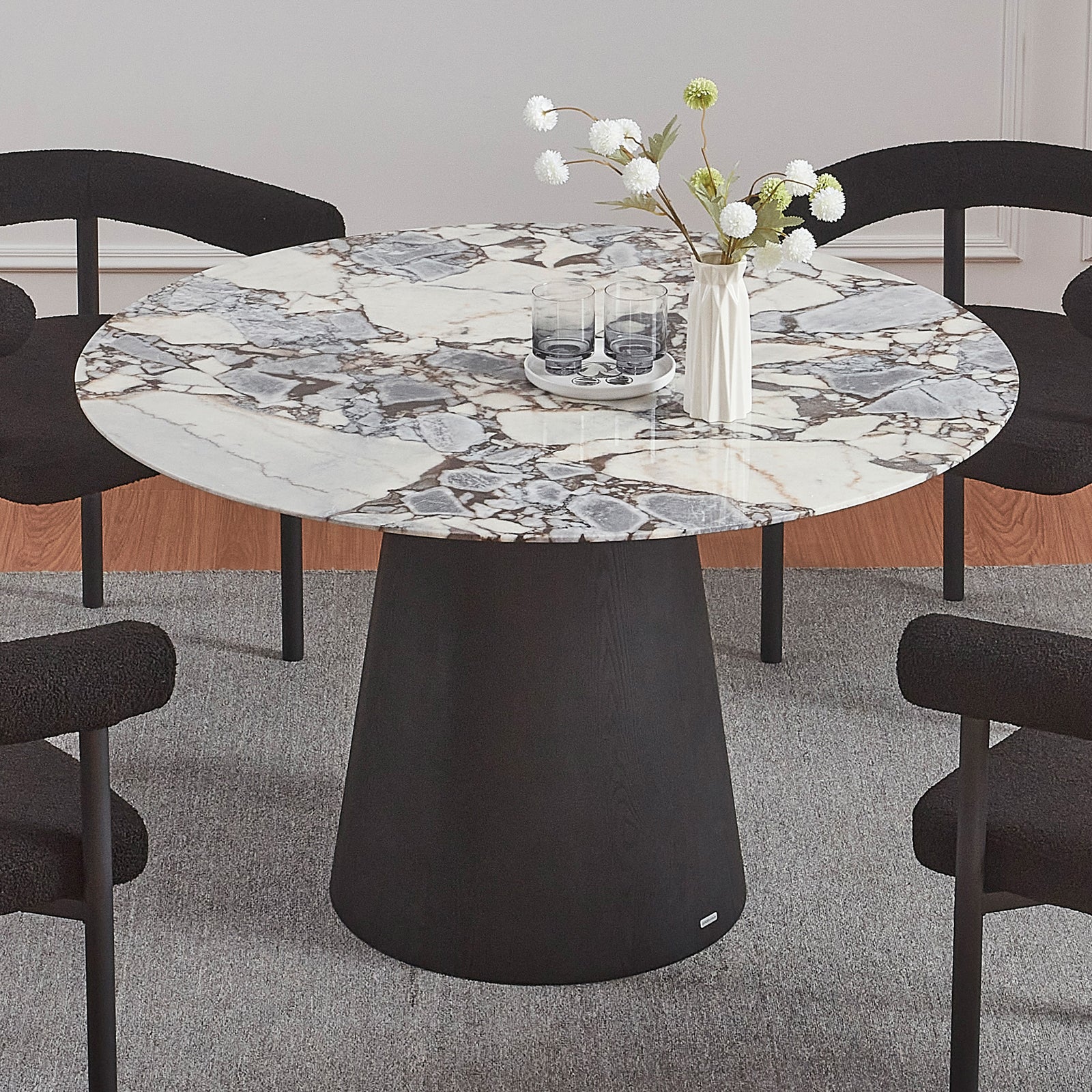 Dina 120cm Round Marble Dining Table in Blue Galaxy Black, featuring a white-and-gray marble top and a solid black pedestal base, surrounded by four black chairs on a neutral rug.