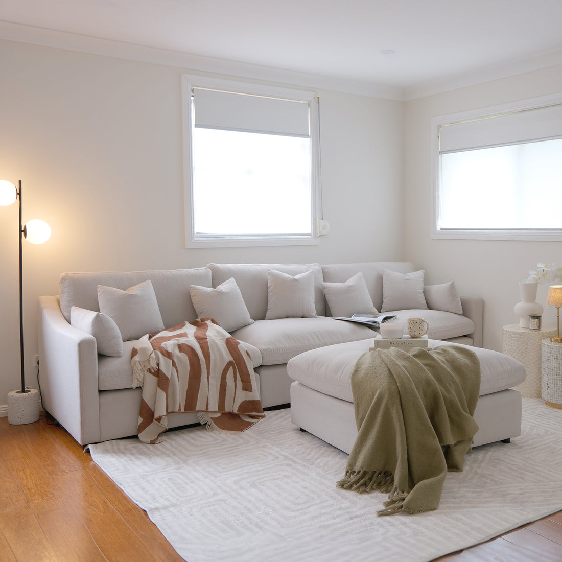 Light beige sectional sofa with matching ottoman styled in a bright living room