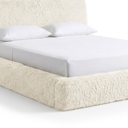 Partial view of a plush upholstered bed on a white background
