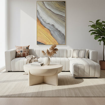 Parisa 4 Seater Tufted Boucle Sofa with Chaise in cream white, featuring channel-tufted upholstery, accompanied by geometric and striped throw pillows, knit throw, and a round neutral-toned coffee table.