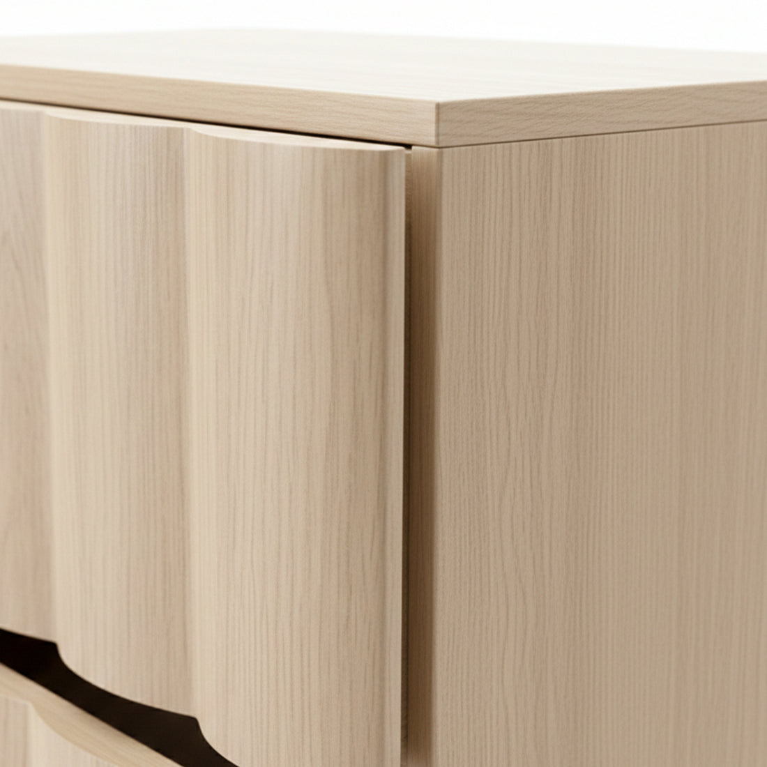 Detail of curved drawer front and wood grain on light wood cabinet corner
