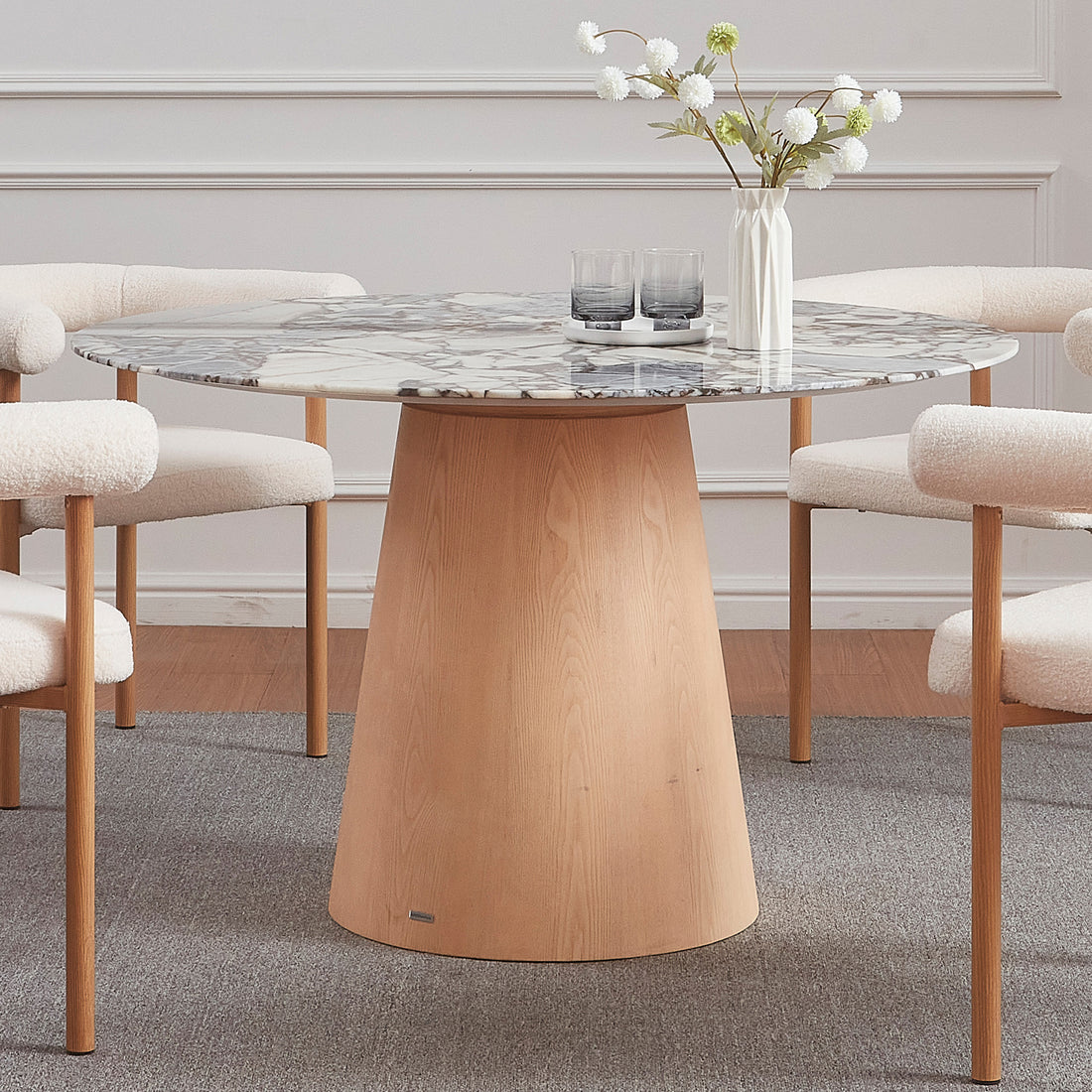 Dina 120cm Round Marble Dining Table in Blue Galaxy Natural features a sleek marble top with unique veining, supported by a flared wooden base, surrounded by four boucle-upholstered chairs.