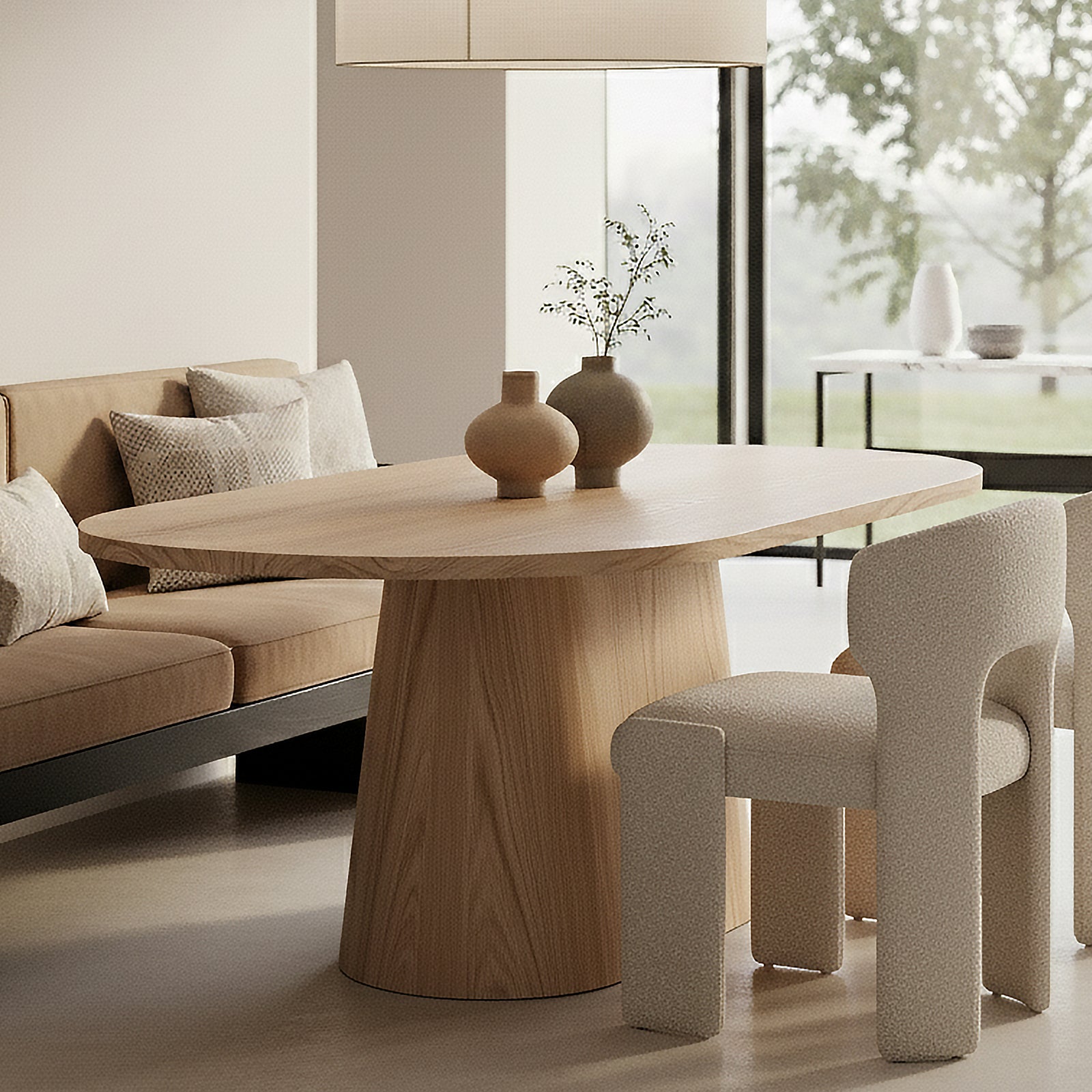 Gigi 180cm Oval Wooden Dining Table in Oak features a light-wood finish, oval shape, and sculptural base, nestled in a minimalist dining nook with elegant decor and soft natural lighting.