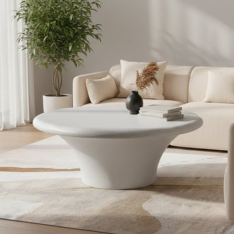 Round white coffee table styled in a living room with neutral sofa and decorative accents