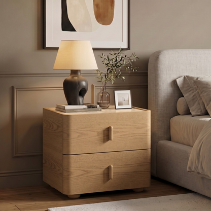 Light wood two-drawer nightstand styled beside a bed in a modern bedroom