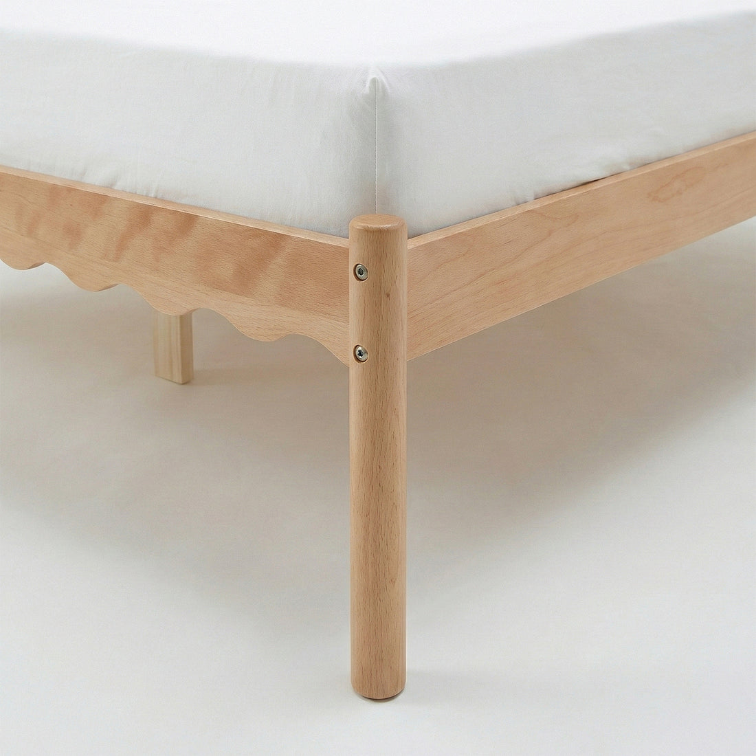Close-up of bed frame corner and leg with white mattress on white background