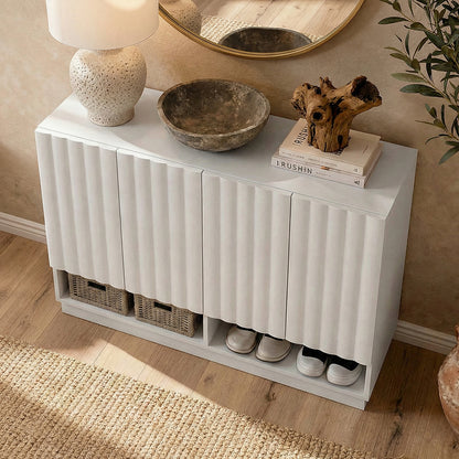 White console cabinet styled in room with lamp, bowl, books, driftwood, round mirror above