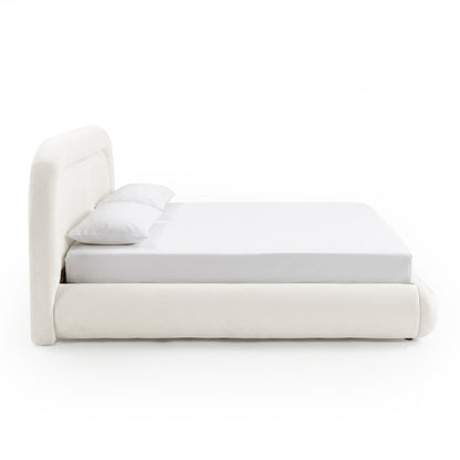 Side profile of a complete low-profile ivory upholstered bed with mattress and pillows