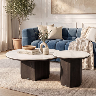 Two nesting round tables styled in a modern living room beside a blue sofa