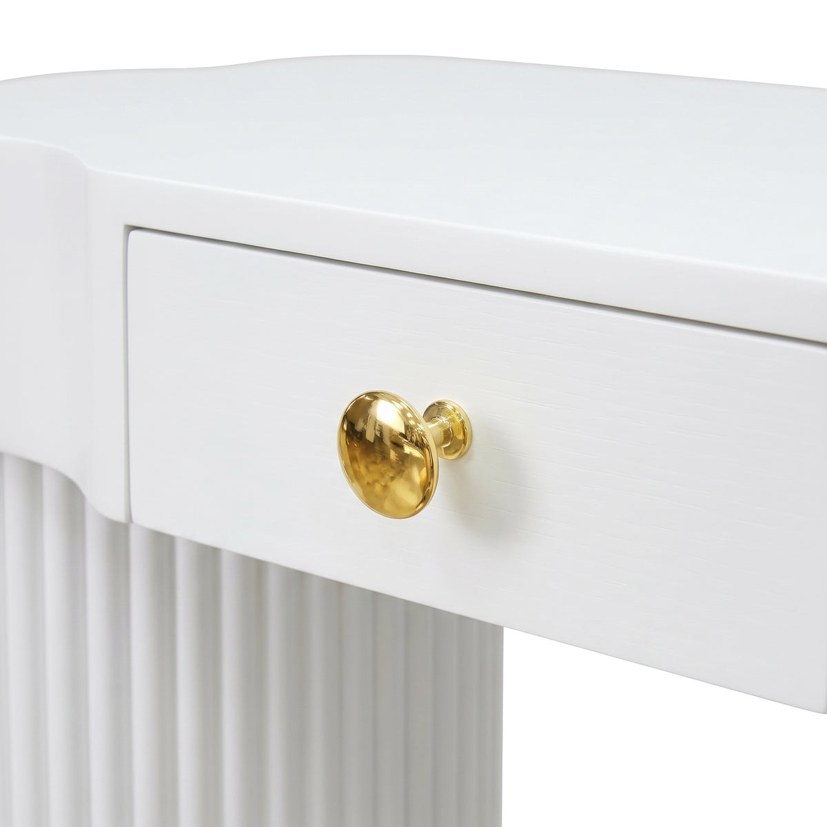 Close-up partial view of a white console table drawer and ribbed leg with gold knob on a white background