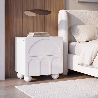 White modern nightstand styled beside a bed in a bedroom.