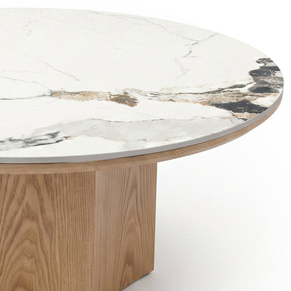 Partial view of a round coffee table with marble-effect top and wood base on white background
