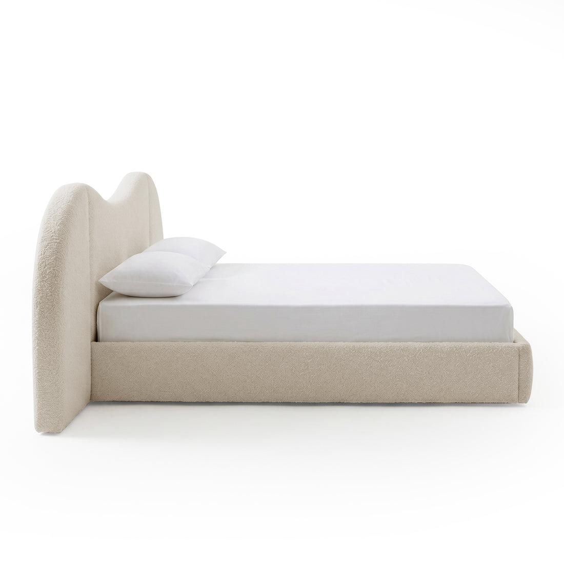 Side view of upholstered bed with white bedding on white background