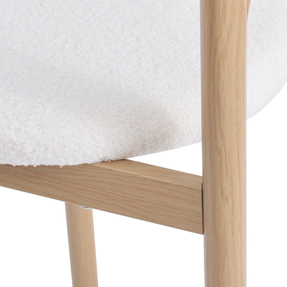Close-up of a chair corner with textured white upholstery and light wood legs on a white background