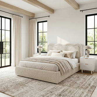 Upholstered bed in a bright, styled bedroom with windows and décor