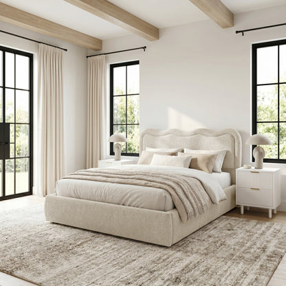 Upholstered bed in a bright, styled bedroom with windows and décor