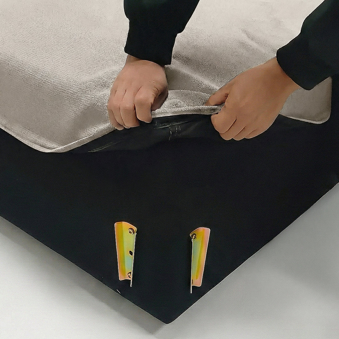 Hands unzipping a beige fabric cover at the corner with metal brackets
