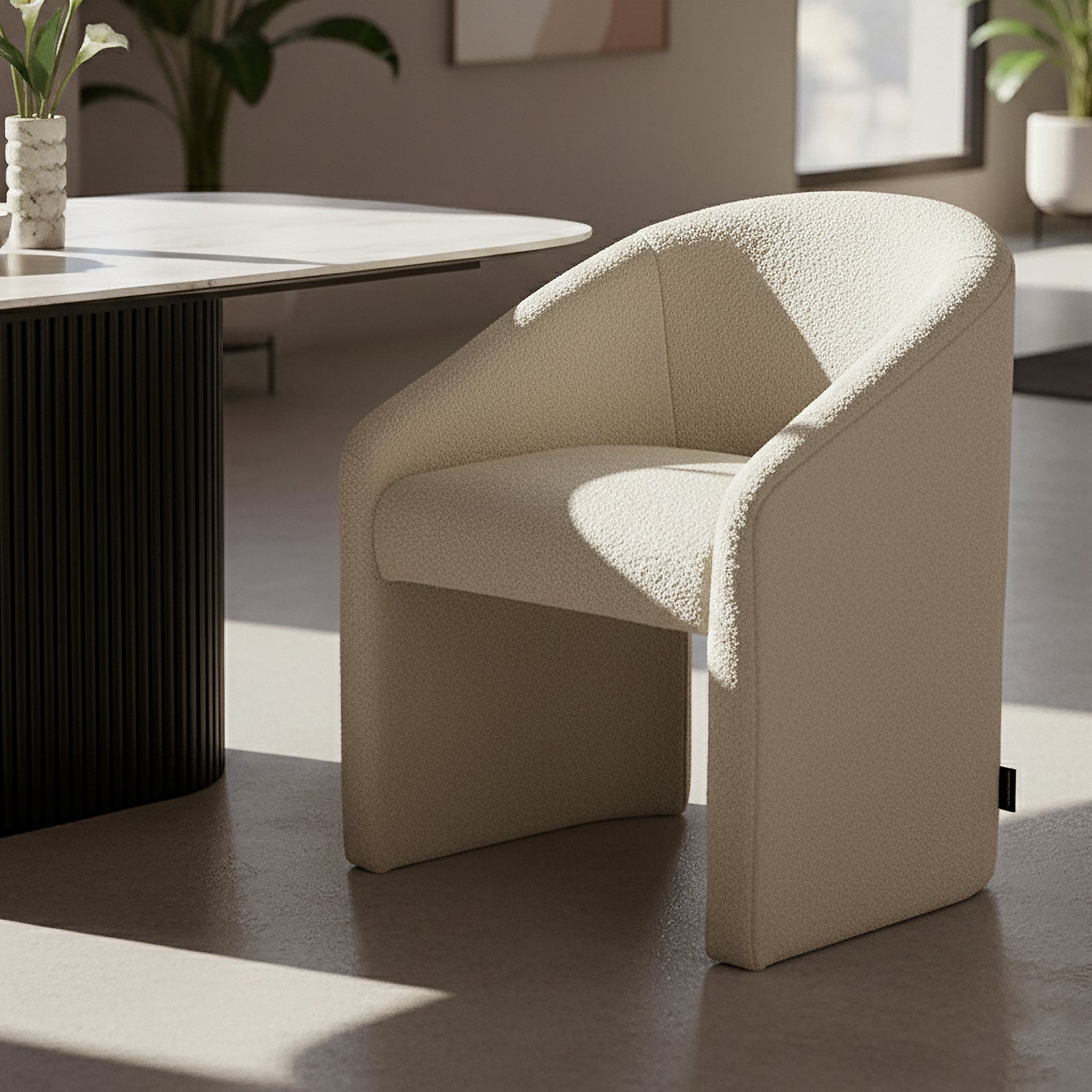 Nuve Bouclé Upholstered Accent Armchair in Cream White, featuring a curved back and soft boucle fabric, placed in a minimalist corner with natural light, near a fluted pedestal table with calla lilies.
