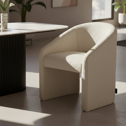Nuve Bouclé Upholstered Accent Armchair in Cream White, featuring a curved back and soft boucle fabric, placed in a minimalist corner with natural light, near a fluted pedestal table with calla lilies.