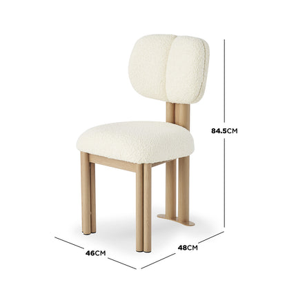 Norii Boucle Fabric Dining Chair in Cream White features an ivory boucle fabric seat and backrest, light wood-look legs, and vertical posts, showcasing a modern, sculptural design.