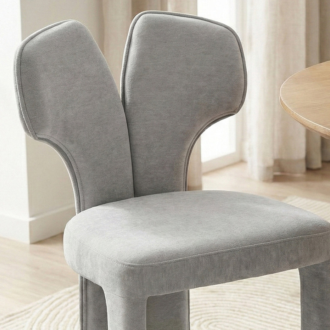 Light gray upholstered chair near window with wood flooring