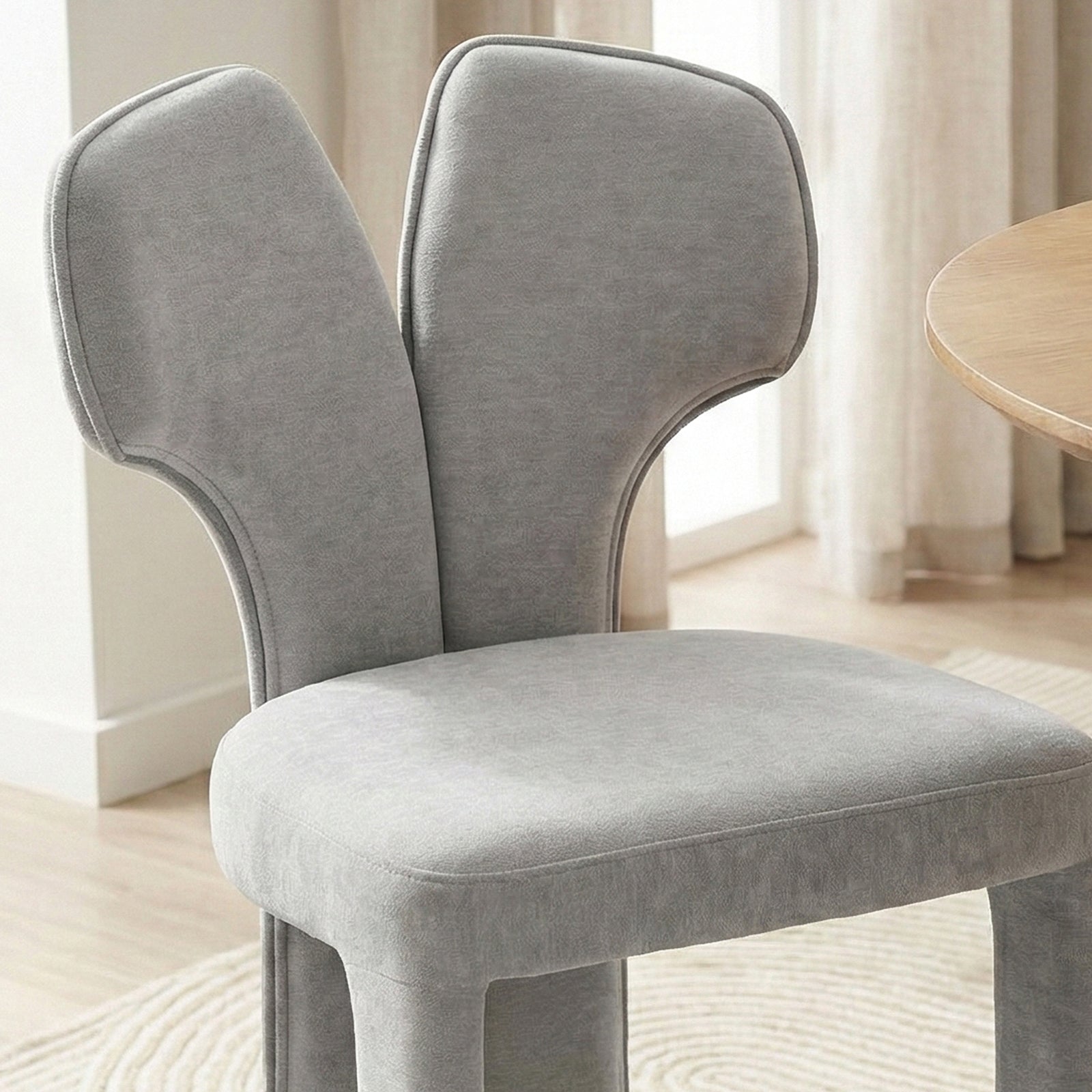 Light gray upholstered chair near window with wood flooring