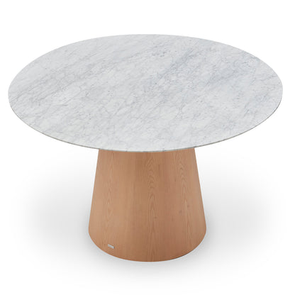 Dina 120cm Round Marble Dining Table in Carrara Natural features a white marble top with gray veining and a tapered wooden pedestal base, creating a refined and inviting dining centerpiece.