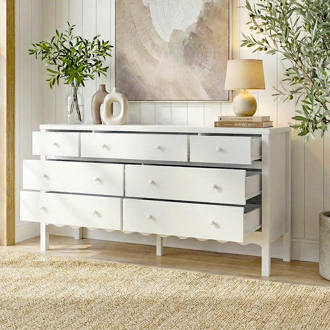 White eight-drawer dresser in a modern room setting with plants and artwork