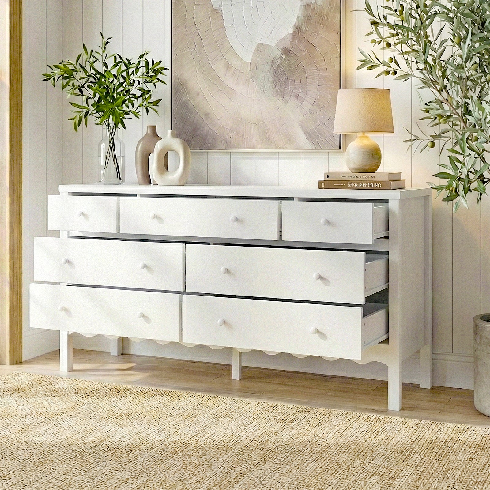 White eight-drawer dresser in a modern room setting with plants and artwork