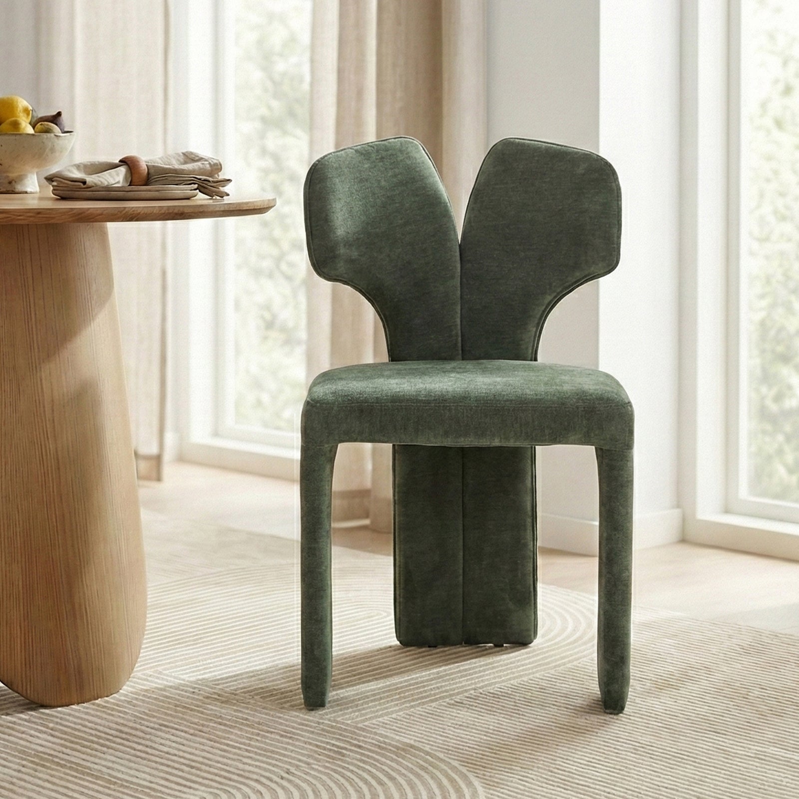 Green wing-back style chair by organic wooden table in natural light