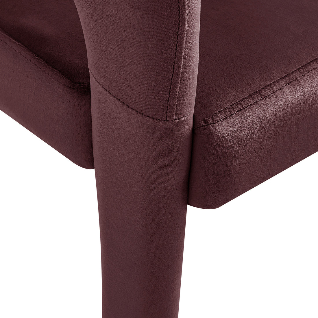Close-up of Eisha Velvet Dining Chair Set of 2 in Dark Plum, showcasing plush burgundy fabric and meticulous stitching on the seat cushion and leg, highlighting its luxurious and modern design.