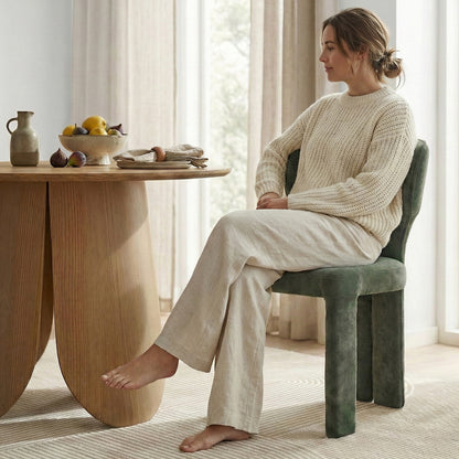 Green upholstered chair at dining table with person seated in stylish interior