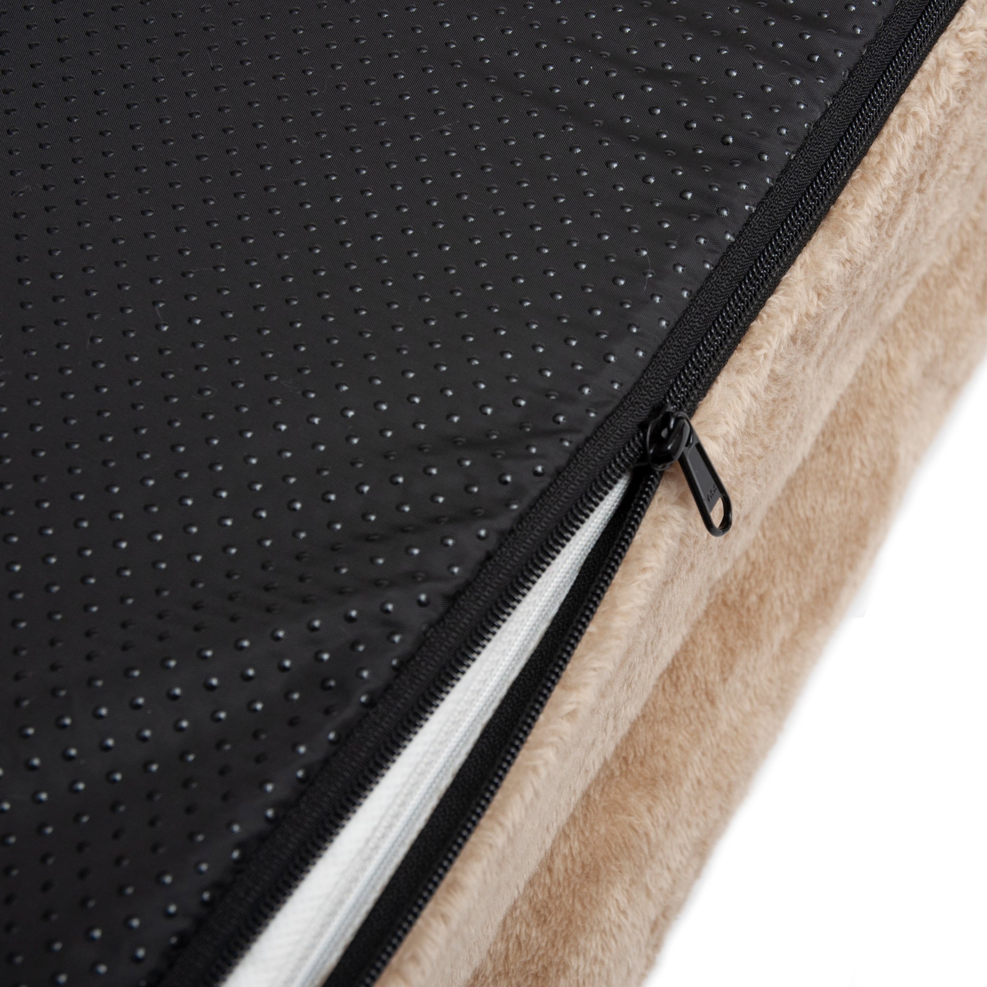 Close-up of beige cushion with black anti-slip underside and partially opened zipper