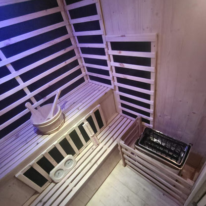 Interior of the Luxo Kiima 3 Person Hybrid Finnish Outdoor Sauna, showcasing tiered wooden benches, a traditional bucket and ladle, heater unit with rock basket, and a mounted thermometer/hygrometer.