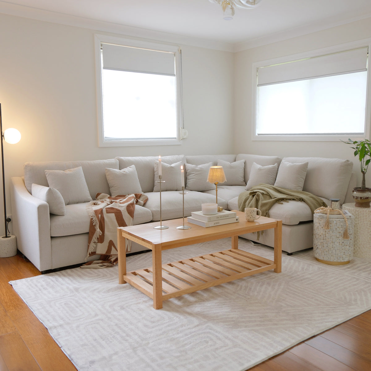 Beige L-shaped sectional sofa in a modern living room with coffee table and decor