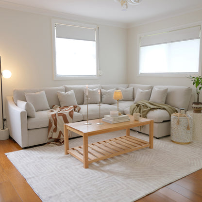 Beige L-shaped sectional sofa in a modern living room with coffee table and decor