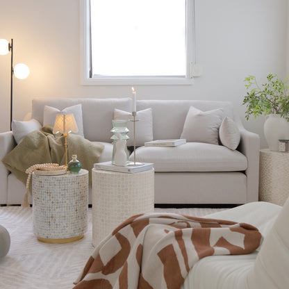 Light grey or beige sofa styled in a bright modern living room with side tables and decor