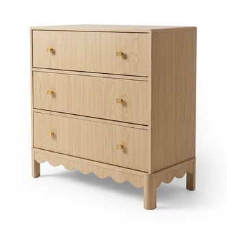Light wood three-drawer dresser with gold knobs on white background