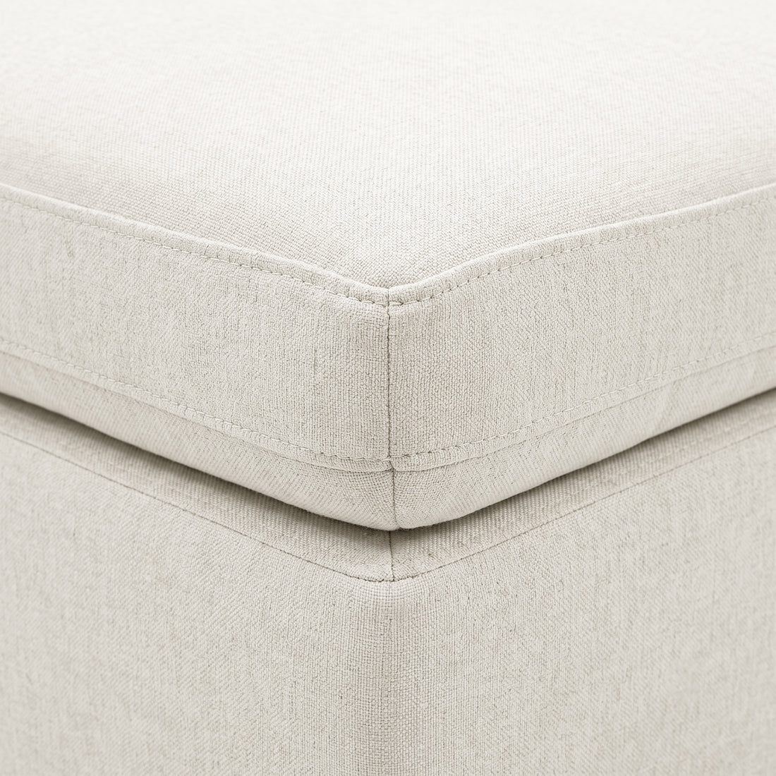 Close-up of cream upholstered cushion corner with stitching and textured fabric