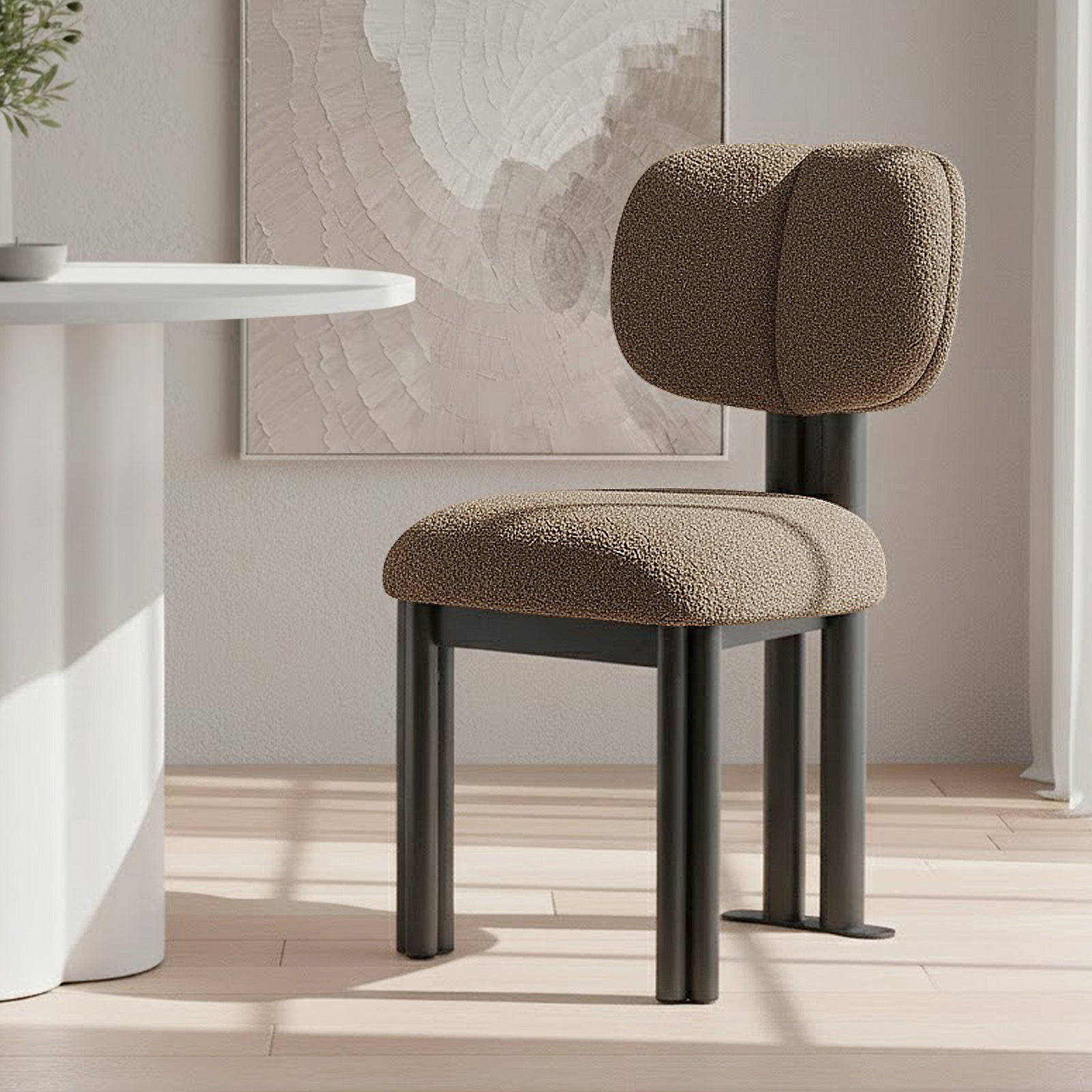 Norii Boucle Fabric Dining Chair in Rust Brown features a boucle-upholstered seat with a split backrest on sleek black legs, set in a modern, neutral-toned interior with an abstract wall art backdrop.