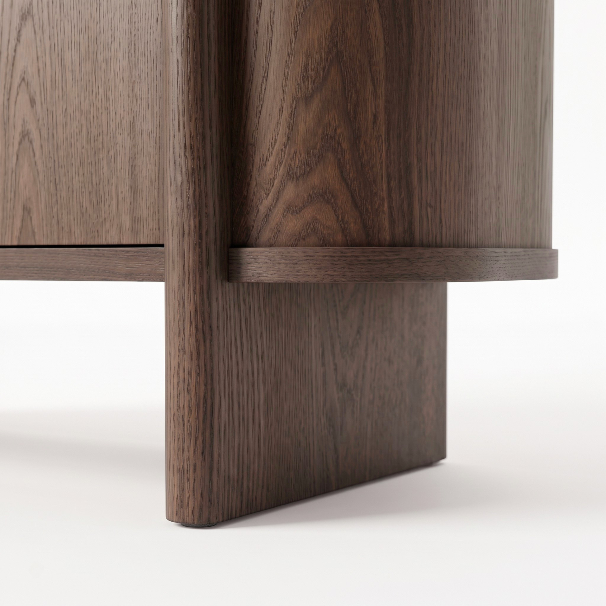 Close-up of the base corner of a dark wood furniture piece on white background