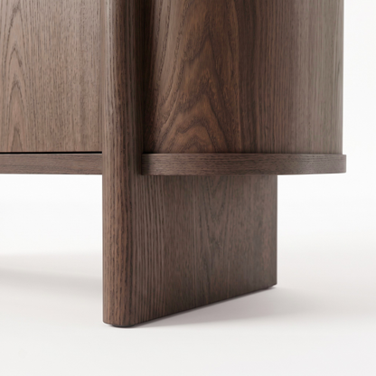 Close-up of the base corner of a dark wood furniture piece on white background