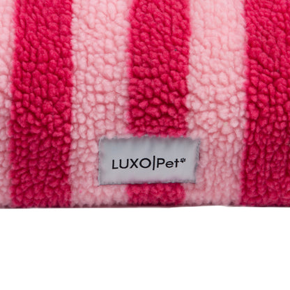 Close-up of pink and fuchsia striped fleece fabric with LUXO|Pet tag