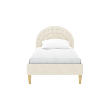 Estilla Velvet Rainbow Bed in Beige features a twin-sized frame with a rainbow-shaped headboard of padded panels, light-wood tapered legs, and a low footboard, showcasing soft-touch velvet upholstery.