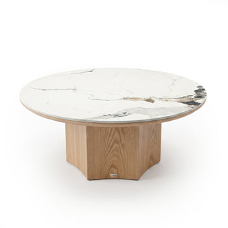 Round coffee table with white marble top and light wood geometric base on white background