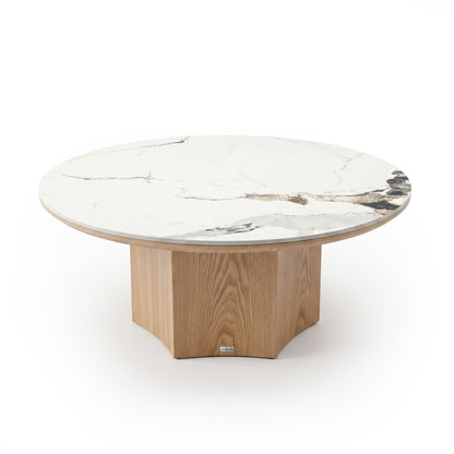 Round coffee table with white marble top and light wood geometric base on white background