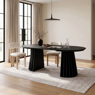 Black oval dining table styled in a bright modern dining room