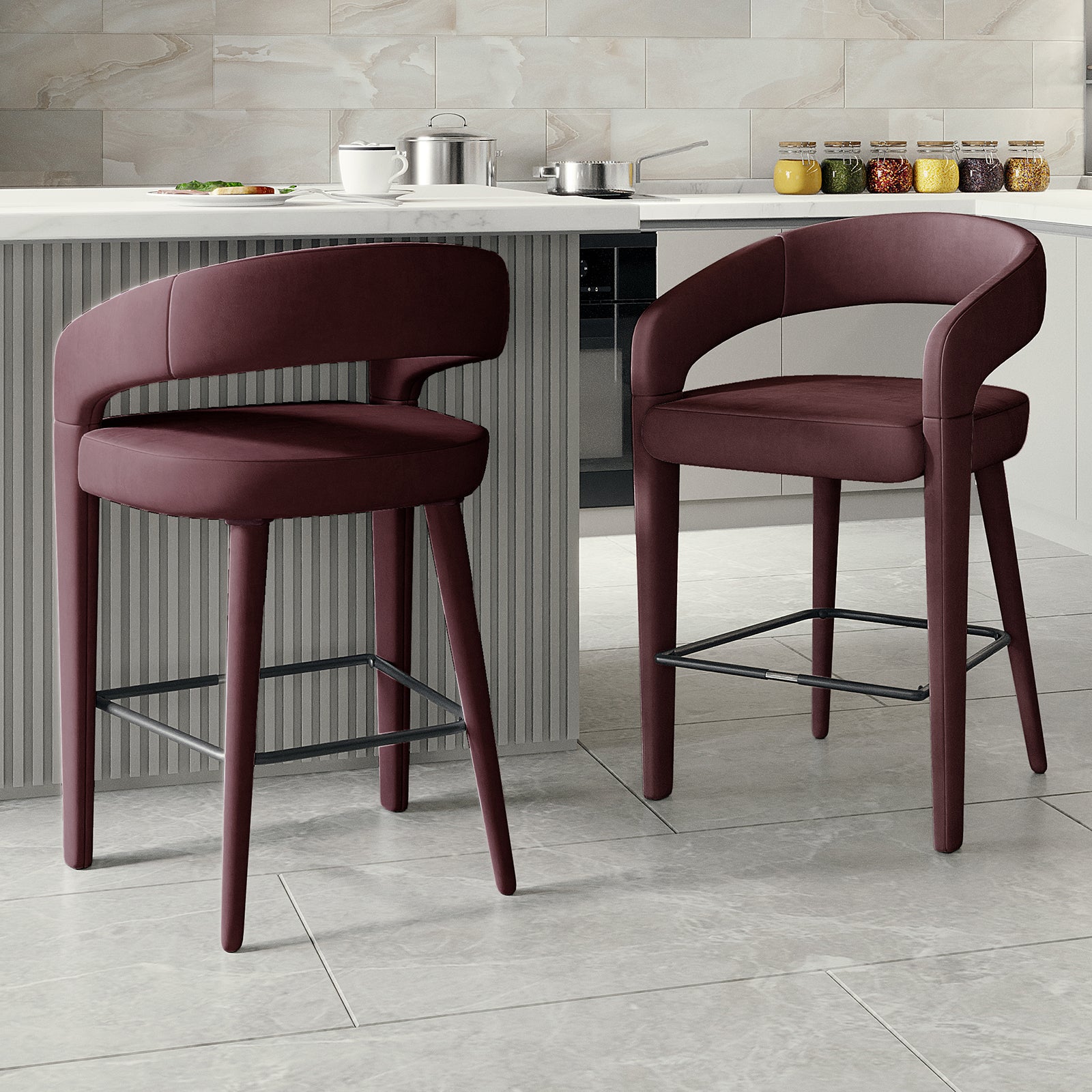 Eisha Velvet Bar Stool Set of 2 in Dark Plum features upholstered stools with rounded backs, padded seats, and slim wooden legs with metal footrests, complementing a contemporary kitchen or breakfast bar setting.