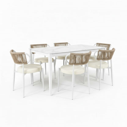 Cabria 7 Piece Sintered Stone Outdoor Dining Set in Beige features a marble-style table with a white frame, surrounded by six chairs with cream cushions and woven rope backrests, perfect for alfresco dining.